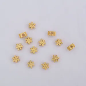 Detailed macro view of gold-plated snowflake charms and striped spacer beads for DIY jewelry