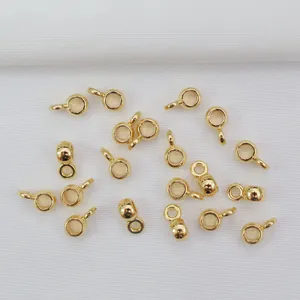 Detail von 14K vergoldeten Schlaufen für DIY-Schmuckherstellung auf weißem Stoff