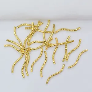 Macro shot of 14k gold-filled curved tube beads with textured engraving for DIY jewelry