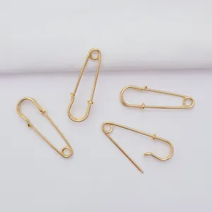 Close-up of 14k gold-filled safety pins on white textured fabric background