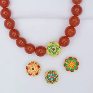 Detail of red agate beads with colorful enamel spacers and gold-plated floral accents