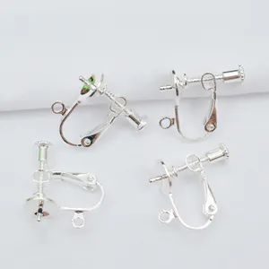 Close-up of four silver screw-on earring converters with DIY loops on white fabric