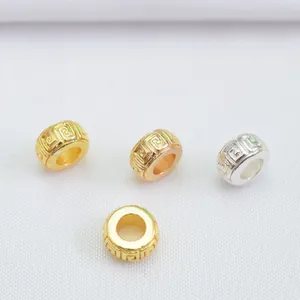 Macro detail of 18k gold-plated 6mm fret pattern spacer beads for DIY jewelry making