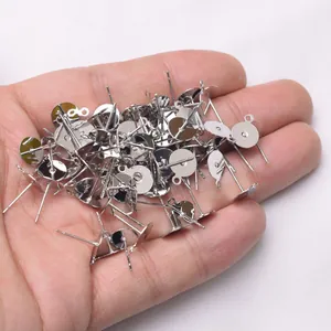Bulk DIY earring studs with flat pads and hanging loops shown on hand, silver plated