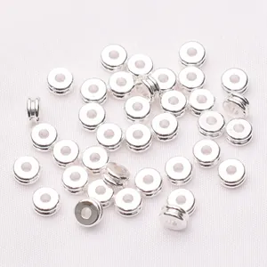 Primer plano de cuentas espaciadoras redondas plateadas con doble ranura para bisutería DIY