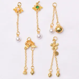 Detailed macro view of five gold-plated charm pendants with pearls and lotus designs