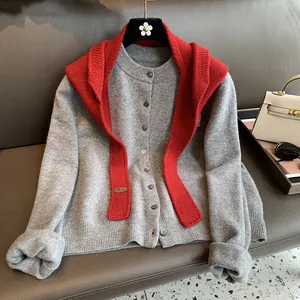 Close-up of soft gray knit cardigan texture with contrasting red knitted shawl detail