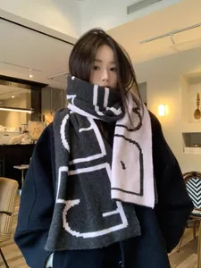 Detail of soft geometric knit scarf with large letters paired with a black winter coat
