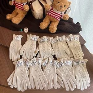 Close-up of cream knit lace hollow gloves with vintage label and wavy cuff design