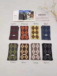 Flat lay of multiple argyle wool scarves in various colors with minimalist tags