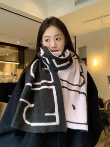 Detail of soft thick scarf with black and pink geometric patterns worn by a model