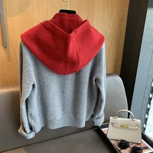 Detail of gray and red contrast knit hoodie showing fine cashmere texture and ribbed cuffs
