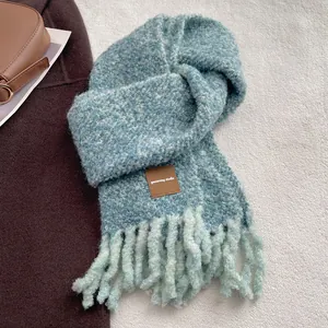 Gros plan détaillé de l'écharpe en tricot bleu et beige avec étiquette en cuir et franges