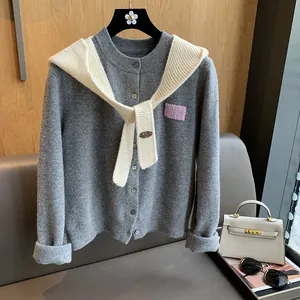 Detail of grey knit cardigan with a white scarf collar and purple accent patch