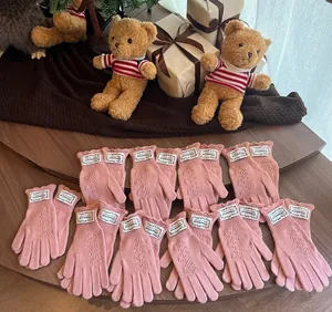 Pink lace hollow knit gloves with wavy ruffles and labels displayed on wooden table