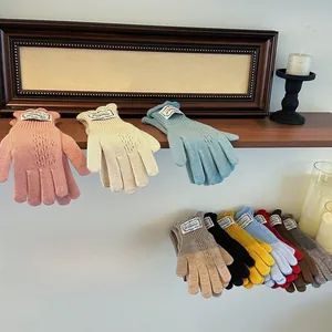 Knitted gloves with diamond hollow patterns displayed on a rustic wooden shelf