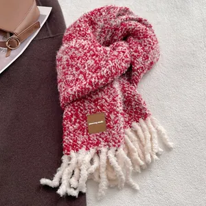 Détail de l'écharpe en laine mélangée rouge et blanc avec pompons épais et logo en cuir