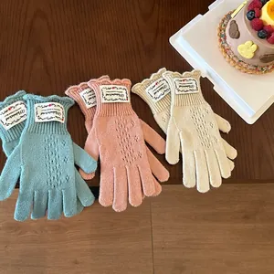 Detailed knit gloves with hollow patterns and ruffled edges in soft pastel colors