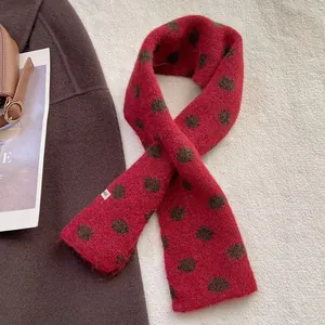 Détail d'une écharpe en tricot rouge à pois marron foncé avec étiquette sur un manteau douillet