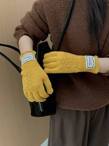 Close-up of yellow lace knit gloves with vintage woven label and floral hollow pattern