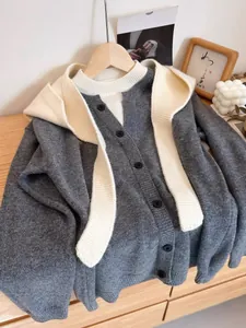Detailed close-up of dark grey buttoned knit cardigan with cream white shoulder scarf