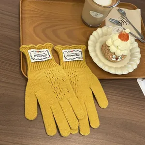 Detail of yellow knit lace gloves with ruffled cuffs and label on a wooden tray