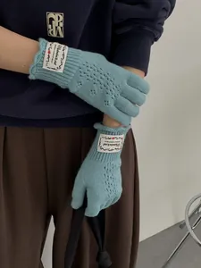 Detail of light blue pointelle knit gloves with a vintage floral fabric label on wrist