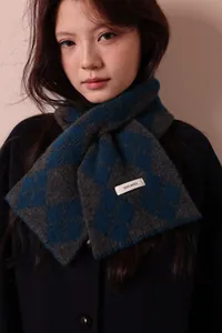 Detail showing the 100% wool label on a gray and blue diamond lattice knitted scarf