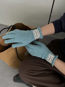 Close-up of light blue knit gloves featuring a heart-shaped cutout and wavy cuff edges