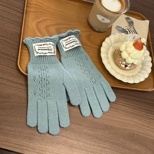 Detail of light blue knit gloves with delicate pointelle lace and ruffled wrist cuffs