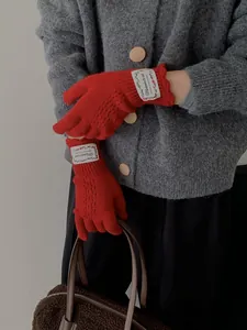 Detail of red hollow knit gloves with vintage label and diamond cutout pattern