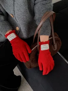 Detail of red hollow knit fingerless gloves with elegant lace crochet pattern and wrist tag