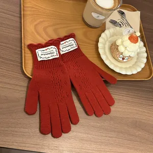 Close-up of dark red knit gloves with delicate hollow lace patterns on a wooden table