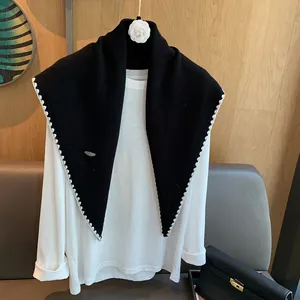 Détail d'un châle en laine tricoté noir avec bords festonnés blancs et t-shirt blanc