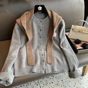 Detail view of grey knit cardigan featuring elegant buttons and a pink flower patch accent