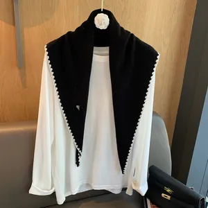 Détail d'un châle triangulaire en laine noire avec une dentelle blanche et des textures