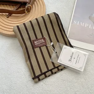 Détail d'une écharpe en coton rayée kaki avec étiquette de marque et labels de mode