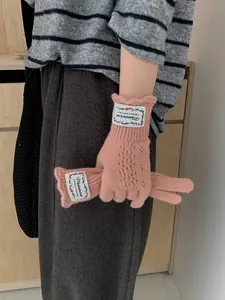 Close-up of pink crochet knit fingerless gloves with lace trim and brand label detail