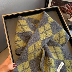 Detailed close-up of the 100% pure wool texture and grey green argyle pattern on scarf