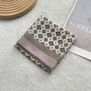 Détail d'un foulard en coton et lin à motif géométrique et bordure ondulée sur peluche