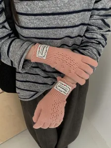 Close-up of pink lace hollow-out knit fingerless gloves with retro patch detail