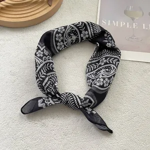 Detail of bohemian black and white floral silk scarf knotted on a white textured background