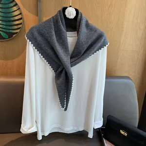Détail d'un châle en laine grise avec bord ondulé au crochet blanc sur bois
