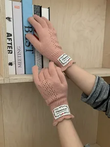 Detail of pink knitted fingerless gloves with hollow lace pattern and vintage woven label