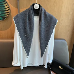 Détail d'un châle en laine gris foncé avec bordure au crochet blanc sur cintre