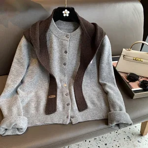 Detailed close-up of grey knitted cardigan with brown shawl and leather label detail