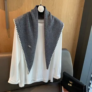 Détail d'un châle triangle en laine tricotée grise avec bords en dentelle blanche