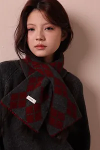 Close-up of red and grey argyle wool scarf with 100% wool material tag on a model