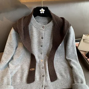 Detailed texture of baby wool knit cardigan and brown shawl with oval brand tag