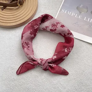Detail of red floral cotton linen scarf featuring white flower patterns and rolled edges